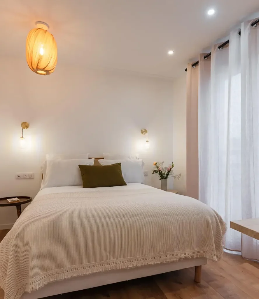 Chambre double avec lit confortable, luminaire design et rideaux clairs